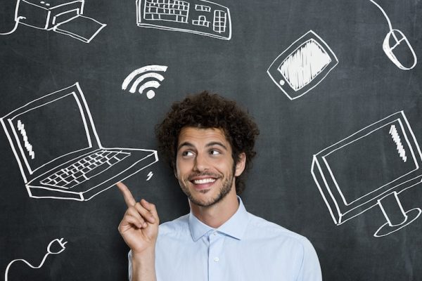 Portrait Of Young Man With Different Computer Technology Over Gray Background